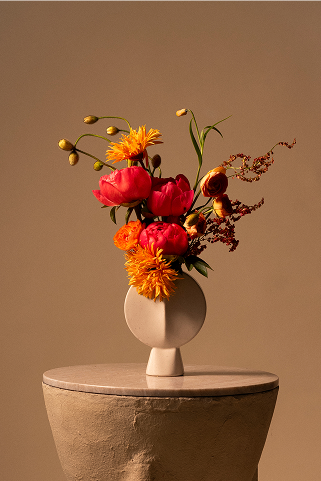 Composition florale dans un vase blanc rond sur socle de plâtre