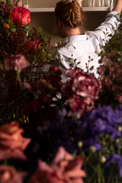 Fleuriste vue de dos parmi les fleurs